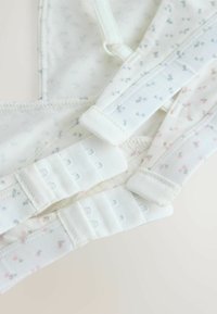 Sutien alb cu un model floral în nuanțe de bleu deschis și roz. Bretele ajustabile și închidere cu clips, dotată cu mai multe cârlige pentru o potrivire perfectă.