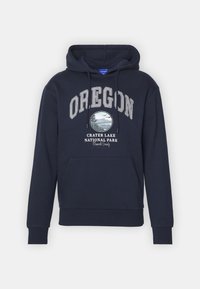 Námořnická modrá mikina s kapucí, která nese text "OREGON" a kruhovou grafiku Národního parku Crater Lake. Obsahuje přední kapsu a kapuci se šňůrkou.