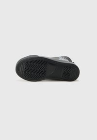 Black rubber sole with textured pattern, smooth at the front and a raised accent at the heel. Reinforced edge for durability.