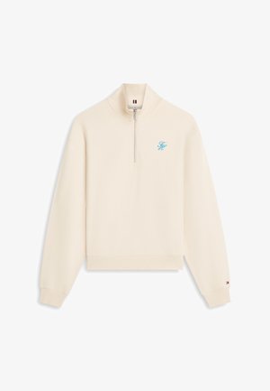 Kremfarget kvart-zipgenser med ribbestrikket krage, mansjetter, kant, liten blå brodert logo på brystet, og liten flaggdetalj på ermemansjetten.