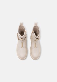 Botines beige de tobillo hechos de cuero suave, con cremallera lateral, herrajes en tono dorado y un forro interior texturizado. Suela gruesa.