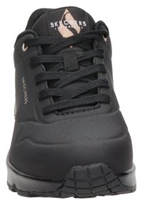 Černé tenisky Skechers s hladkým syntetickým svrškem, kulatou špičkou, šněrovacím designem, texturovanými detaily a robustní gumovou podrážkou.