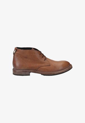 Bottes de cheville en cuir marron avec un fini lisse, bout arrondi et semelle contrastante. Elles disposent de lacets fins et d'une petite boucle au niveau du talon.