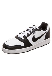 Czarnobiałe buty sportowe wykonane ze skóry i materiałów syntetycznych. Posiadają białą podeszwę, czarny logo w kształcie „swoosh” i białe sznurówki. Okrągły kształt palców.