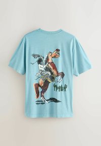 Lyseblå bomulds-T-shirt med et grafisk tryk af en hest og rytter, med kaktusser i baggrunden. Korte ærmer, rund hals.