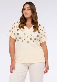 Cremefarvet V-hals T-shirt med korte ærmer, der har gyldne leopardprint-detaljer over fronten for et struktureret udseende.