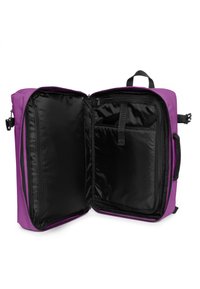 Bolsa púrpura con un interior negro. Presenta una apertura con cremallera, múltiples compartimentos y asas de tela para un transporte fácil.