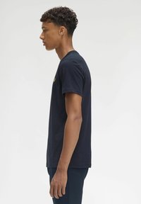 Camiseta de algodón negra con mangas cortas y cuello redondo, con un pequeño gráfico en el pecho y un corte relajado.