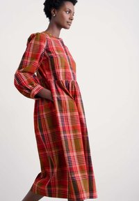 Rotes kariertes Kleid mit puffärmel, geknöpften Ausschnitt und seitlichen Taschen. Hergestellt aus einem strukturierten Stoff mit kontrastierenden grünen und schwarzen Linien.