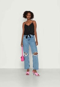Černý cropped top s knoflíky a uvázaným předním uzlem, světlezelené široké džíny s roztržením, růžové sandály na podpatku, odpovídající růžová kabelka.
