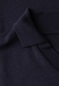 Tissu tricot marine avec une finition texturée, présentant un col et un ourlet côtelés. Matériau doux et flexible avec des coutures lisses et uniformes.