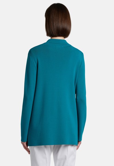 Cardigan en tricot long à manches longues en teal, avec un col à revers et une fermeture ouverte. L'arrière a un design lisse avec un ourlet droit et une texture minimale.