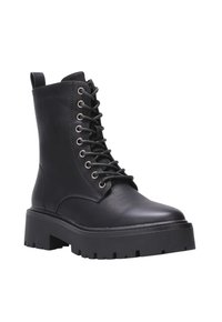 Bottines en cuir noir avec une semelle épaisse, bout rond et fermeture à lacets à l'avant. Équipées d'œillets en métal argenté et d'une languette à l'arrière.