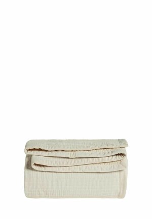 Beige gesteppte Decke ordentlich gefaltet auf weißem Hintergrund, zeigt die weiche Stoffstruktur und die Details der Nähte.