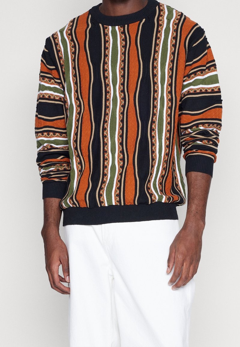Strickpullover mit oranges, grünes und schwarzes vertikales Streifendesign und weißen Akzenten. Gerippte Manschetten und Saum, strukturiertes Muster im gesamten Pullover.