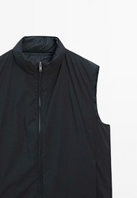 Gilet sans manches zippé noir avec col montant, présenté sur fond blanc, montrant le devant et le côté droit.