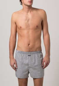 Boxer a righe da uomo in una miscela di cotone, caratterizzati da strisce orizzontali bianche e nere, vita elastica e chiusura anteriore con bottone.