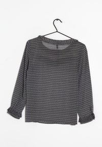 Camicia a maniche lunghe bianco e nero con scollatura a barchetta, caratterizzata da un tessuto strutturato e polsini arricciati.