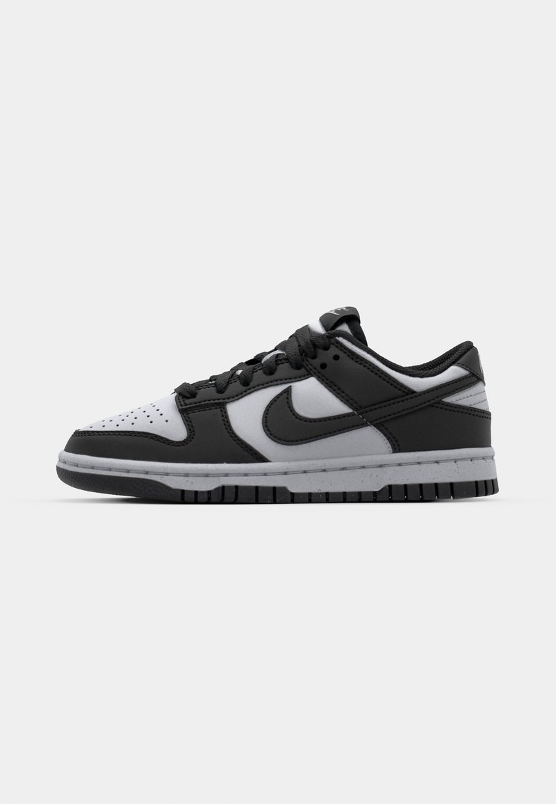 Sneaker basse Nike Dunk in nero e grigio con punta forata, dettagli in pelle liscia e suola in gomma con pattern testurizzato.