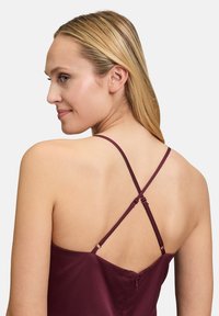 Burgundowa sukienka na ramiączkach z regulowanymi krzyżującymi się paskami, miękka w dotyku, z zamkiem błyskawicznym z tyłu. Gładkie wykończenie materiału.