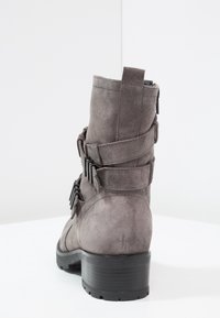 Gray suede ankle boot featuring a chunky black heel, three decorative straps with metal accents, and a side zipper for easy access.