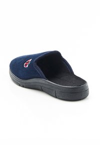 Pantuflas sin cierre de color azul marino, hechas de un tejido texturizado, con una plantilla acolchada y una suela de goma negra para mayor tracción. Pequeño logo de acento.
