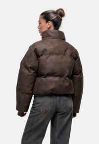 Bruine nepleer cropped pufferjack met logo in reliëf op de achterkant, voorzien van een hoge kraag en ton-sur-ton stiksels.