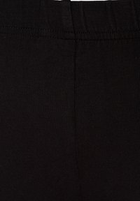 Black ribbed leggings featuring a stretchy waistband and smooth texture, designed for comfort and versatility in wear.