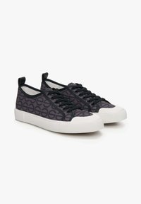 Zwarte canvas sneakers met een gestructureerd patroon, ronde neus, witte rubberen zool en zwarte veters met een hielstrook.