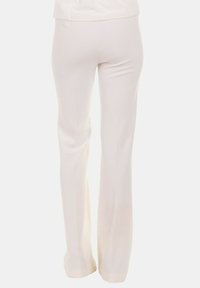 Pantaloni bianchi svasati in tessuto morbido con vita aderente e cuciture minime, caratterizzati da un design semplice e pulito.
