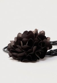 Mustast kangast lille juukseaksessuaar mitmekihiliste kroonlehtedega, kinnitatud mustale elastsele paelale. Sile tekstuur kergelt gradiendi toonis.