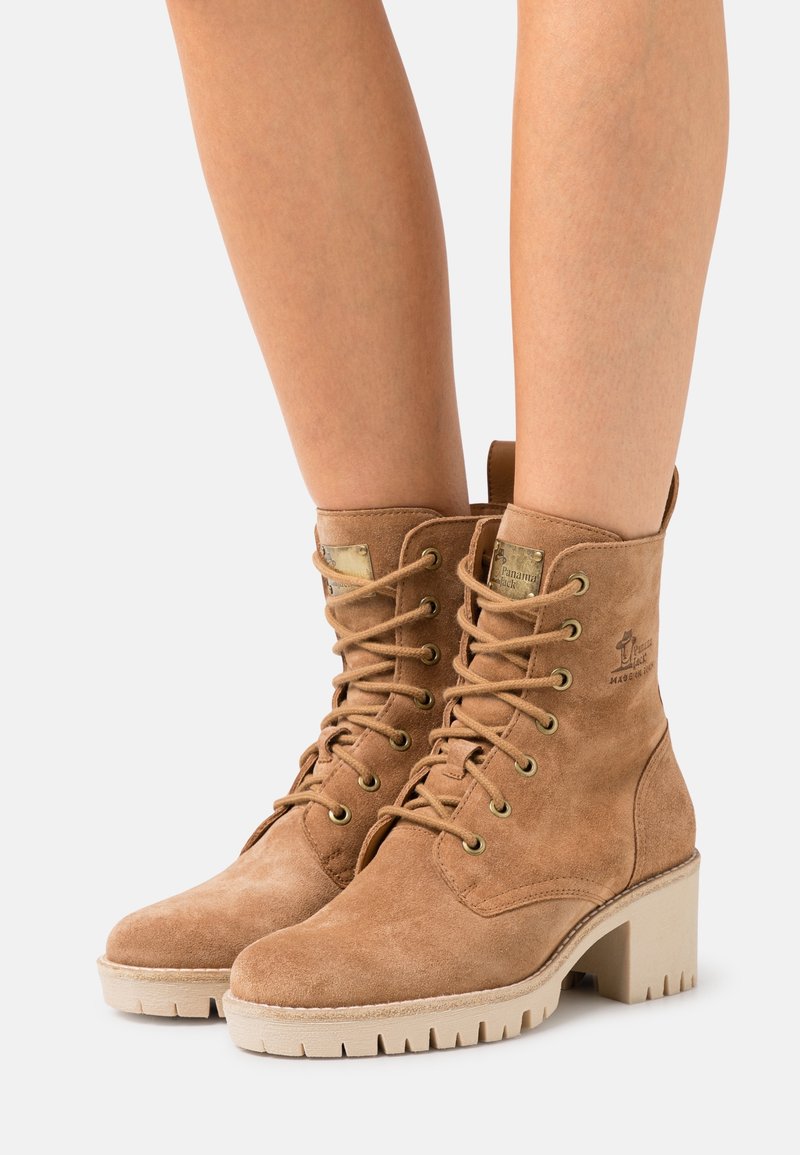 Bottines en suède tan à lacets avec un talon sérré, dotées d'œillets en métal, d'un logo embossé et d'une semelle en caoutchouc texturé.