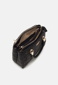 Černá prošívaná kabelka se zlatými detaily, dvě přihrádky otevřené, ukazující béžový interiér a kapsu na zip, s připevněnými rukojeťmi.