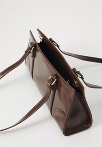 Borsa a mano in pelle marrone con finitura lucida, forma rettangolare, doppi manici e apertura con zip. Dotata di accessori in metallo argento.