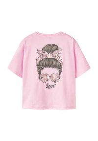 Lyserød T-shirt med en afslappet pasform, der har et grafisk motiv af en kvinde med en knold, iført hjerteformede solbriller og et mønstret hovedbånd, mærket "Kærlighed."