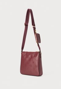 Bolsa de ombro em couro bordô com padrão em relevo, fecho com zíper, alça ajustável e pequena pochete destacável. Textura suave e forma estruturada.