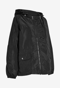 Czarna kapturowa kurtka wykonana z lekkiego, błyszczącego materiału. Posiada zamek błyskawiczny z przodu, elastyczne mankiety oraz kieszeń zapinaną na zatrzask po lewej stronie.