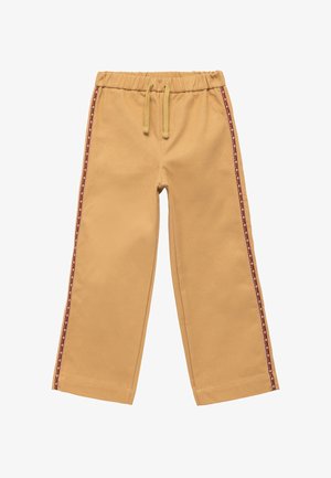 Pantalones de algodón beige con cintura elástica y cordón. Rayas de patrón rojo y blanco que recorren el lateral. Diseño de pierna ancha.