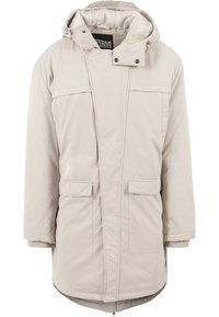 Parka beige clair avec capuche, fermeture éclair, deux poches avant et surface texturée. Présente une coupe décontractée et des éléments ajustables.