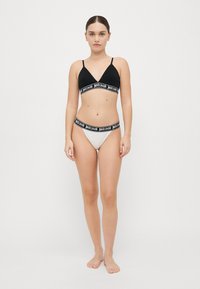 Bralette triangle noir et culotte grise avec une bande décorative noire portant le texte "justcavalli". Tissu lisse, design minimal.