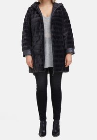 Kurtka puchowa w ciemnoszarym kolorze z poziomym pikowaniem, kapturem i błyszczącymi rękawami. Połączona z szarym swetrem dzianinowym i czarnymi jeansami.