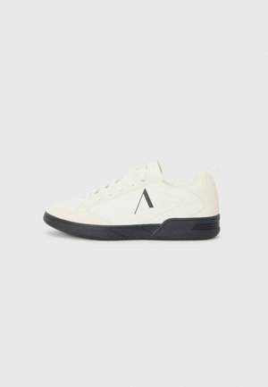 White athletic shoe featuring a textured upper, black sole, and a geometric accent on the side. Laces with a flat, round design complete the look.