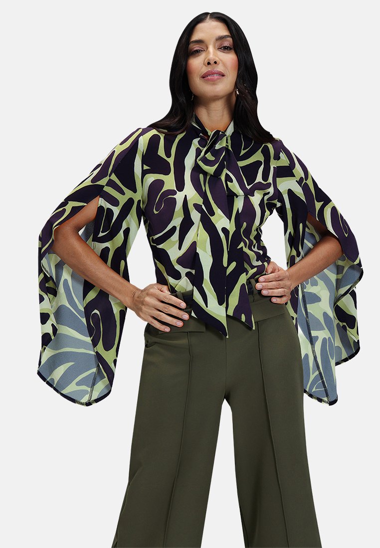 Multicolored blouse features a green and black abstract pattern, wide sleeves, and a tied neck detail, paired with olive green pants.