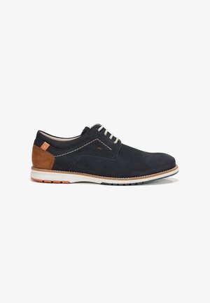 Chaussures en daim navy avec des accents beige, des coutures blanches contrastantes et une semelle en caoutchouc texturée avec des détails bleus et orange.