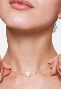 Gouden draad ketting met een enkele witte parel. De parel is rond en glanzend, wat contrasteert met de dunne, elegante draad.