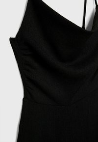 Robe en tissu noir texturé avec de fines bretelles et un décolleté drapé en col bénitier.