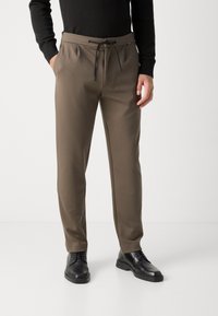 Slim-fit, taupe trenirke s elastičnim pojasom i vezicom, sa bočnim džepovima i glatkim, teksturiranim materijalom.