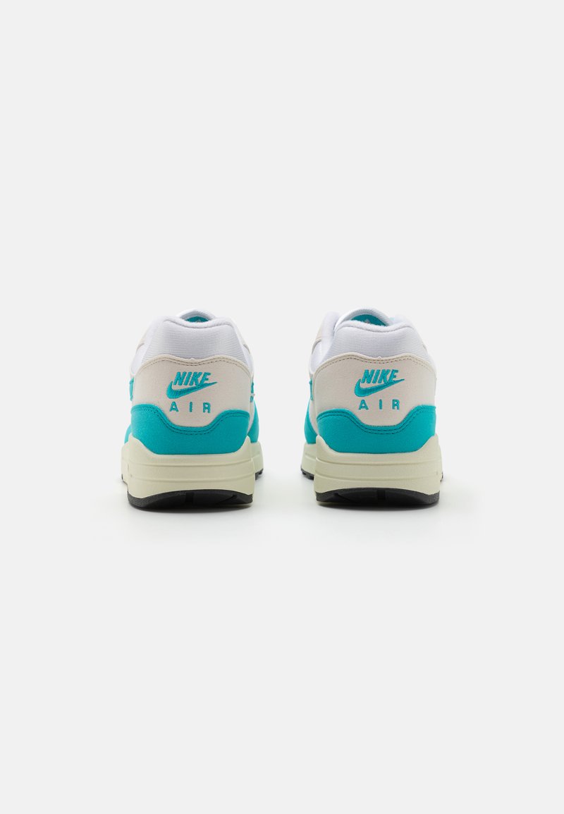 Nike Air-schoenen met een wit en turquoise kleurenpalet, een gevoerde kraag en een gestructureerde bovenkant, voorzien van een crème zool en een zwarte buitenzool.