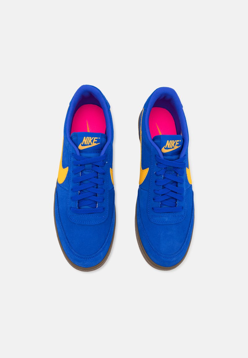 Sneakers blu in pelle scamosciata con swoosh giallo Nike, caratterizzati da punta arrotondata, lacci piatti e rivestimento interno rosa. Suola in gomma per aderenza.