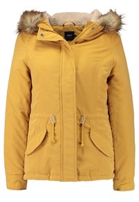 Żółta pikowana kurtka z futrzanym kapturem, zamkiem błyskawicznym z przodu oraz szczegółami typu toggle. Posiada dwie boczne kieszenie i miękką, teksturowaną podszewkę.